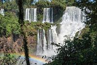Durchguck  Am tiefsten Punkt des unteren Weges wird man erst die immense Breite der Felsstufe gewahr, in der die Wassermassen der drei Fälle Adán, Eva und Bosetti so zusammenfließen, dass sie nahezu ununterscheidbar geworden sind. Auch hier haben wir das Glück, dass die Mittagssonne genau richtig steht, um das Foto mit einem weiteren Regenbogen zu krönen.
