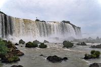 Letzte Wege  Noch bevor wir am Besucherzentrum den Bus verlassen, ist das Kameraproblem durch geduldiges Abtupfen gelöst und wir streben zum Vorplatz, um unseren Fahrer zu treffen. Da wir nur 2½ Stunden unterwegs waren, ist er noch nicht da, taucht aber nach einer Viertelstunde mit seinem VW-Taxi auf. Wenig später sind wir wieder an der Grenze und reihen uns in eine etwas längere Schlange vor nur einem geöffneten Schalter ein. Als wir dran sind, stößt unser Fahrer plötzlich aus einem Nebeneingang zu uns und sorgt auf portugisisch dafür, dass ich nicht nur einen Ausreisestempel in den Reisepass bekomme, sondern dass die Beamtin schmunzelnd auch noch nachträglich den vergessenen Einreisestempel zufügt. Will alles seine bürokratische Ordnung haben!  Zurück am Hotel beschließen wir, uns gleich zum Flughafen bringen zu lassen. Dort läßt sich die Zeit bis zum Abflug besser aushalten, als in der schwülwarmen Rezeption des Hotels. Unser netter Chauffeur hilft beim Gepäckeinladen, bringt uns zum Aeropuerto und nach einem herzlichen Dankeschön verabschieden wir uns mit einem großzügigen Trinkgeld von ihm.
