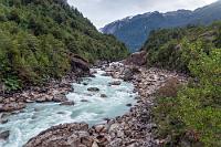 Río Ventisqueros  Bereits am Vortag auf dem Darwinfrosch-Lehrpfad hatte mein linkes Knie zu muckern begonnen, mich aber nicht weiter behindert. Heute ist der Beginn des Weges noch recht eben, dann beginnt der Pfad aber stetig zu steigen und neben kurzen, in den Fels gehauenen Treppchen dominieren bald teilweise halsbrecherische Felsverhaue, tückische Baumwurzeln und aufgrund des häufigen Regens sehr matschige Abschnitte. Es ist anstrengend, zwei, drei Rastplätze laden aber bei schönen Ausblicken über den Río Ventisqueros zur kurzen Erholung ein.
