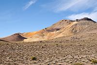 Der Höhepunkt!  In zumindest einer Hinsicht kann man diesen unscheinbaren Hügel als Höhepunkt unserer Reise betrachten. An ihm vorbei führt nämlich die vom Salar de Surire kommende Paßstraße, die an dieser Stelle mit etwas über 4700 m den höchsten Punkt unserer Reise markiert. Der dunkle 'Hügel' im Hintergrund reckt sich 5300 m in den Himmel.  Eine äußerst seltsame Erfahrung, sich an diesem Ort und für die nächsten hundert Kilometer dauerhaft in Hochlagen oberhalb des höchsten Gipfelniveaus der Alpen zu bewegen.  Diese Höhe haben wir erst  2017 in Peru  wieder getoppt ;-)