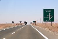 Die Preussen Südamerikas  Ich hoffe, es fühlt sich kein mitlesender Chilene durch diese irgendwo aufgeschnappte Charakterisierung verunglimpft, aber manche Sitten und Gebräuche scheinen zumindest stark von deutschen Einwanderern beeinflußt oder initiiert zu sein. So zum Beispiel die Angewohnheit meist männlicher Angehöriger der Mittel- und Oberschicht, selbst bei schweißtreibensten Temperaturen in Schlips und Anzug aufzutreten, oder – wie hier – der Brauch des exzessiven Schilderaufstellens.  Die Panamericana führt auf hunderten von Kilometern durch nichts als Wüste. Gelegentlich mal ein Hügel, ein aus drei Gebäuden bestehender Rastplatz, die obligatorische Straßenkapelle (ein Herrgottswinkel auf Marienbasis), eine Überlandleitung.... und natürlich: Straßenkreuzungen! Meist handelt es sich nur um einen Abzweig – aber was die Chilenen daraus machen... Respekt!  Man sollte meinen, eine etwas verbreiterte Straße samt mittlerer Abbiegespur und zwei Schildern auf jeder Seite sei bei einer Verkehrsfrequenz von ca. ¼ Auto/min. völlig ausreichend. Ha, weit gefehlt! Wie schön ein chilenisches Abbiegeprojekt angelegt sein kann, beweist dieses Foto. Ich zähle alleine auf der rechten Seite 11-12 Schilder (die gelben Richtungspfeile in der Kurve nicht mitgezählt!), mal zwei (denn auf der anderen Seite sind es nicht weniger), macht 24 Verkehrsschilder! Und umständlicher kann man eine Abzweigung auch nicht erstellen. Wohlgemerkt: dieses Bild zeigt keinen Einzelfall, sondern die Regel!  Ich werd' Schildermaler in Chile. 'Nen bombensichereren Job kannste gar nicht kriegen ;o)