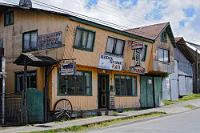 Isla de Chiloé  Chiloé ist nach Feuerland die zweitgrößte Insel Südamerikas. Mit 2500 mm Niederschlag im Jahr ist das Klima sehr feucht, was sich in den gelinde gesagt etwas abgeliebten Holzbauten dokumentiert. In Dalcahue, wo wir eine Übernachtung hatten, sehen viele der Häuser so wie dieses aus, welches wir fotografierten, als es uns noch nicht nach einem warmen Essen gelüstete. Da unser Hotel außer Frühstücksbuffet nichts zum Essen anbot, machten wir uns am Abend auf die Suche nach einem Restaurant. Dies war leichter gesagt als getan, denn im Gegensatz zum Tagesbetrieb scheinen nach 18:00 Uhr alle Restaurants zu schließen. Nach langer Suche und diversen Befragungen von Einheimischen fanden wir am Hafen noch genau eine geöffnete Gaststätte – offensichtlich zugeschnitten auf die Bootsleute und Fischer, die hier gewaltige Portionen verdrückten. Auch wir wurden von der mütterlichen Wirtin sofort aufs Freundlichste bedient und sahen uns ebenfalls nach kurzer Zeit mit einem leckeren, aber äußerst fetthaltigen Essen ausgestattet, welches noch Tage später vorhielt...