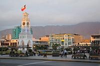 Kulturzentrum  Das im 16. Jahrhundert gegründete Iquique war lange Zeit nur ein unbedeutendes Fischerdörfchen unter peruanischer Flagge. Erst mit dem Seehafen, über den der aufkommende Salpeter- und Guanohandel abgewickelt wurde, kam der Wohlstand, der die Stadt zum Zentrum der Región de Tarapacá werden ließ. Im 'Salpeterkrieg' kam Iquique 1879 nach einer Seeschlacht dann unter chilenische Herrschaft.  Der in dieser Seeschlacht gefallene Kommandant Arturo Prat wird seither in einer jährlichen Zeremonie als Volksheld gefeiert. Das Bild zeigt die zentrale 'Plaza Arturo Prat' mit dem malerischen Uhrturm, der in seinem Sockel eine pompöse goldene Büste des Feldherrn beherbergt. Der Platz bietet zudem mit dem 'Teatro Municipal' ein Kulturzentrum, in dem an diesem Abend ein Freiluftkonzert eines landesweit verehrten Chansonniers stattfand – deshalb die Fernsehkameras rechts im Bild...