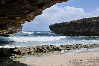 Kalkig  Der Einschnitt der "Boka Kalki" zieht sich weit in die karstige Küstenlandschaft hinein, beidseitig von überhängenden Auswaschungen des Korallenkalks begrenzt. Der hintere Teil der Bucht, durch den sich der Zugangsweg schlängelt, ist von einem – für Inselverhältnisse üppigen – Wäldchen bewachsen, wohltuend schattenspendend und Heimat von Leguanen und Vögeln wie dem kleinen Gesellen aus dem vorigen Bild.