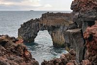 Basalttor  An der Ostspitze der Insel lockt ein skurriler Leuchtturm auf zwei Stelzen zu einem weiteren Halt. Eine breite Treppe führt auf einen umlaufenden Aussichtssteg, den wir uns aber verkneifen, da ein schmaler Pfad zwischen rostrot verkrusteten Felsen direkt an das Steilufer führt. Fasziniert begegnen wir hier erstmals den typischen Basaltformationen, auf die wir im weiteren Verlauf der Reise noch sehr häufig treffen werden.