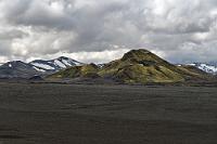 Highland Rover  Der Duster nebst Insassen kämpfen sich tapfer im Schritttempo voran und wir alle befürchten das Schlimmste – denn über 20 km liegen noch vor uns! Glücklicherweise ist aber nach ein paar Kilometern Schluß und wir alle haben es schadlos überstanden. Etwas später treffen wir auf einen Ranger, der uns freundlich einen Flyer zum korrekten Fahren im Hochland in die Hand drückt und uns genau erklärt, was alles unter "off-road" fällt und damit sakrosankt ist...  Die Landschaft ist mondhaft, riesige Lava- und Aschefelder,  rotschwarze Vulkane, grünbewachsene Berge und vereinzelte Schneereste unter tiefverhangenem Himmel. Doch je mehr wir uns unserem Ziel, dem "Bílastæði við Landmannalaugar", dem Parkplatz vor der Furt am Landmannalaugar nähern, desto mehr klart es auf und es kommt tatsächlich die Sonne raus!