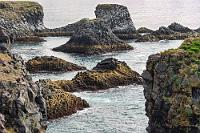 Vogelrevier  Arnastapi besteht aus kaum mehr als ein paar Häusern, einigen Hotels und einem Parkplatz für die Besucher der Felsenküste. Immer öfter kommt jetzt die Sonne heraus, so dass wir sogar unsere Jacken im Auto lassen können. Mit Aussicht auf die versprochenen zahlreichen Seevögel klemme ich mir die Telekamera unter den Arm und los geht's über rollstuhltaugliche Drahtgitterwege an die Küste, deren Basaltstelenstruktur sich in den vorgelagerten kleinen Inseln fortsetzt. In der Tat gibt es tausende von Seevögeln, die sich aber meist auf den äußersten Klippen aufhalten und nicht gewinnbringend abzubilden sind. Macht aber nichts, denn es gibt auch so genug zu sehen.