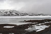Zwischenwinter  Wir stehen wie immer um 7:00 Uhr auf und genießen unser Spa-Erlebnis im kühlen Bad und interessant nach Schwefel duftendem warmen Wasser (das kalte Wasser kommt glücklicherweise aus einer anderen Zuleitung und darf uneingeschränkt getrunken werden!). Anschließend sind wir dann auch schnellstens im Frühstücksraum, um wenigstens heute eine Chance auf Joghurt und Orangensaft zu haben, die am gestrigen Morgen schon 'aus' waren.  Als der Himmel beginnt, sich zu strukturieren, machen wir uns auf den Weg nach Seyðisfjörður, einem – wie der Reiseführer verspricht – niedlichen, kleinen Fährort. Wieder führt die Straße über einen Pass, vereinzelte Wolken hängen tief, es schneeschauert leicht und auch hier liegt auf den Seen noch eine Eisdecke.
