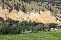 Buntstein  Dem Fraser River werden wir auf unserer Reise jetzt noch mehrfach in ganz unterschiedlichen Landesteilen begegnen, denn er folgt einem langen, gewundenen Lauf, bis er bei Vancouver in die Georgia Strait mündet. Wir fahren auf dem HWY 99, welcher aus einer malerischen Mittelgebirgsregion langsam auf das ausgedehnte Fraser Plateau ansteigt, einer relativ flachen Landschaft, die sich aber durchgängig auf 1000 m Höhe ausbreitet. Es ist wenig Verkehr, was sich auch nicht ändert, als der HWY 99 an der Einmündung in den Cariboo HWY endet. Wir folgen jetzt dem HWY 97 weiter nach Norden, sehen uns aber nach nur 3 km zu einem spontanen Halt genötigt, da die gelborange leuchtende Flanke einer Hügelkette nach ein, zwei Fotos schreit. Offensichtlich fanden auch die Straßenbauer diese Sandsteinformation so reizvoll, dass sie extra eine Haltebucht auf diesem Straßenabschnitt eingerichtet hatten.