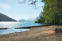 Lake Cowichan  Wir haben prima geschlafen und in der Hoffnung auf ein paar Schnappschüsse von vorwitzigen Hörnchen gehen wir am frühen Morgen schon vor dem Frühstück nochmals den Weg hinunter zum See. Am Vorabend war der Badestrand brechend voll gewesen und auf dem See kreuzten zahlreiche Boote. Heute morgen hingegen ist es menschenleer, der See liegt unberührt in strahlendem Sonnenschein und in der absoluten Stille liegen die Hörnis wohl auch noch im Tiefschlaf, denn ich muß mein Tele nicht einmal bemühen. : Lake Cowichan