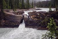 Natural Bridge  Der Weg zum Emerald Lake fällt auch den Witterungsbedingungen zum Opfer und so bleibt es bei der Besichtigung der "Natural Bridge", einer durchbrochenen Felsformation im Kicking Horse River, die in der Tat eine brückenähnliche Kreuzung des Flusses ermöglicht, was aber aus Schutzgründen nachvollziehbarer Weise verboten ist. Dafür gibt es eine hübsch-häßliche Betonbrücke direkt daneben, von der aus man einen guten Blick auf dieses Naturmonument hat.  Als der zweite Reisebus mit Japanern eingetroffen ist, wird es Zeit, die Weiterreise anzutreten. Wir fahren wieder zurück Richtung Alberta und Icefields Parkway und vorbei an Lake Louise. Richtig: Vorbei! Das Schild am Highway sagt: Lake Louise Parkplatz voll. Ausweichparkplatz mit Busshuttle zum See 3 Kilometer weiter. Wollen wir uns das antun? Nein! Vielleicht ist es jetzt etwas verspätet zu beichten, dass wir um eine Reihe von touristischen 'Musts' einen weiten Bogen gemacht haben. Nur der Vollständigkeit halber: Wir waren weder in Vancouver, noch in Victoria, Tofino, Emerald Lake, Lake Louise, Banff, Calgary, Kamloops und Kelowna. Wer will, kann an dieser Stelle immer noch den Besuch unserer Seite abbrechen. Wir könnten's ihm/ihr nicht verdenken... ;o)