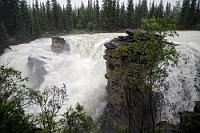 Pfützen Parcour  Der touristische Zeitplan nimmt keine Rücksicht auf Wetterunbilden und so ist auch der Parkplatz an den Fällen ordentlich gefüllt. Zusätzlich sind gerade auch noch zwei Reisebusse voller Japaner angekommen, die bereits vor den Bussen schon mit beschirmten Selfies anfangen.  Wir bewegen uns 'pfützenhüpfender' Weise von einem Aussichtspunkt zum Nächsten, immer darauf bedacht, bei der kurzfristigen Entnahme der Kameras aus den Plastiktüten keine Regenspritzer auf die Optiken kommen zu lassen. Richtig herausfordernd wird's nahe am Fall, als zu dem Regen noch die Gischt dazukommt.