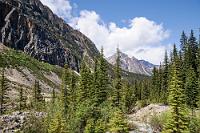 Wer sagt's denn...?  Nach 14 km auf der engen Serpentinenstraße erreichen wir den offensichtlich neu angelegten, großzügigen Parkplatz. Der Ausblick auf die Wand des Bergmassivs sieht nicht gerade verheißungsvoll aus – Nebelschwaden hängen bis fast ins Tal des Gletscherflusses. Doch oh Wunder, während wir uns warm anziehen, beim präventiven Klobesuch noch ein wenig hadern, stiehlt sich leise ein Sonnenstrahl durch den Dunst. Außer uns sind noch eine Menge anderer Besucher hier und alle Blicke richten sich erwartungsvoll nach oben. Wir ziehen auf dem gleichfalls neu eingerichteten (und weitgehend barrierefrei gestalteten) Weg Richtung Gletschersee und mit jeder Minute wird die Sicht besser und der Nebel verzieht sich.