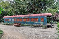 Estación  Wir nähern uns einem Kiosk, der in Würdigung des Ortes "Station" getauft wurde. Ein paar Meter weiter erinnert ein etwas in die Jahre gekommener Waggon an eine Zeit, als der Botanische Garten noch von der Eisenbahnlinie der Region Antioquia angefahren wurde. Ob der im Pflaster angedeutete Schienenverlauf allerdings der Realität entsprach, darf bezweifelt werden, denn bei dem Radstand des Waggons dürften die engen Kurven kaum befahrbar gewesen sein. Wir nehmen Platz an einem der Tische beim Kiosk, um unseren Durst zu stillen. Wir freuen uns, dass es hier die von uns favorisierte Citruslimo gibt und ein paar Schokoriegel können zum Auffüllen unserer Naschvorräte auch nicht schaden. Die Verkäuferin legt Maren einen kleinen Riegel hin. Nein, bitte die große Packung. Sie legt einen größeren Riegel hin. Maren zeigt auf das Paket mit den 12 Riegeln, die Verkäuferin legt es auf den Tresen und weist Maren vorsorglich darauf hin, dass dieses aber ziemlich teuer sei – umgerechnet 25,- €! Maren schluckt, ist überzeugt, beschränkt sich auf 4 große Riegel und spendet 2000 $ Trinkgeld, was nun die Verkäuferin wiederum sehr freut :-).