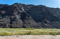 Ai-Ais  Der mit vielen positiven Attributen bedachte Ort Ai-Ais am Ende des Fish River Canyons ist sicherlich für viele Rheumakranke ein interessantes Ziel, weil sie sich in den von mineralstoffreichen Thermalquellen gespeisten Bädern des modernen Spas eine Linderung erhoffen. Für Tagestouristen, die sich eine besondere Attraktion erwarten, ist die zugängliche 'Thermalquelle' – ein ummauerter, von einem blubbernden Betonrohr mit Heißwasser gespeister kleiner Tümpel – eher enttäuschend. Viel mehr her macht die landschaftlich sehr schöne Anfahrt auf Serpentinen hinunter ins Flußtal, in deren wogenden Schilfwiesen u.a. die Fish River Wanderung beginnt oder endet. Wenige Kilometer weiter mündet das, was vom Fluß noch hier unten ankommt in den Oranje, den Grenzfluß zu Südafrika.