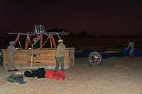 Genug Gas an Bord?  Pünktlich rufen uns die beiden Piloten zum Briefing zusammen und nach Abgleich der Namenslisten mit den vollständig erschienenen 32 Teilnehmern werden jeweils 16 auf die beiden heute startenden Ballons aufgeteilt.  Man unterliegt leicht dem Klischee von Afrika, dem heißen Kontinent. Wir sind zwar nahe am Äquator, aber immerhin auf der Südhalbkugel und damit jetzt fast im Winter. Tagsüber erreicht die Temperatur meist angenehme 23°C, Nachts kann es aber – zumal in der Wüste bei sternenklarem Himmel – recht frostig werden.