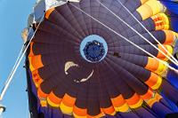 Luftloch  Das Volumen der Warmluft in den riesigen Hüllen muß gigantisch sein, denn obwohl das vom Piloten bediente "Ablassventil" minutenlang geöffnet bleibt, sinken wir nur langsam dem Boden entgegen. Erst, als wir nur noch zwei, drei Meter über Grund schweben und die Fangleinen den Boden berühren, schließt Ruan das "Ventil" und mehrere herbeilaufende Teammitglieder ergreifen die Leinen.