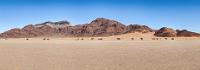 Paramount Panorama  Als nachträgliches Geburtstagsgeschenk für mich war Maren schon bei der Reiseplanung auf die Möglichkeit einer spektakulären Ballontour über die Dünenlandschaft von Sossusvlei gestoßen. Mit dieser Idee rief sie bei mir als gerade retiriertem Flieger eine große Begeisterung hervor. Bereits Zuhause hatte Maren für den Morgen des nächsten Tages eine solche Tour im Internet gebucht.  Wir fahren noch entlang faszinierender Straßenbegleitpanoramen auf dem Weg zu unserem heutigen Ziel, als links neben der Straße die Gebäude des Veranstalters  "Namib Sky"  in Sicht kommen. Da es sehr windig ist, bietet sich eine Nachfrage an, wie realistisch ein Start am nächsten Morgen wohl ist. Eine nette junge Mitarbeiterin bestätigt uns auch erwartungsgemäß, dass der Flug am nächsten Morgen bereits gecancelt sei, bietet uns aber eine Umbuchung auf Übermorgen an.