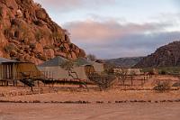 Zinnoberrot  Darüber müssen wir erst einmal schlafen. Am nächsten Morgen liegt das Camp in zauberhaftem Sonnenaufgangslicht und nachdem wir uns wider Erwarten problemlos der Körperpflege unter der heißen Dusche im kalten Draußen hingegeben haben, gehen wir hungrig und mit Fleecejacken bewaffnet zum Frühstück in das ebenfalls frische Restaurant. Nach den ersten Tassen heißen Kaffees sind wir schon fast davon überzeugt, die vorabendlichen Ereignisse nur geträumt zu haben.  Jetzt schnell zum Zelt zurück, um den Rest an warmer Kleidung überzuziehen, denn pünktlich um 8:00 Uhr startet die Wüstensafari in den offenen Jeeps.