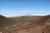 Sendero No.13  Die gut markierten Wanderwege sind leicht zu bewältigen, völlig schattenlos aber recht schweißtreibend, so dass man ausreichend Wasser dabeihaben sollte. Wir befinden uns auf einem Höhenzug zwischen dem Volcán de la Botija und der Montaña Samara und folgen dem Sendero No.13. Hier rötlichbraun gefärbte, kleine Lavabröckchen, zuvor große, karstige Brocken schwarzer Schlacke inmitten von glatt erstarrten Lavaströmen der Montaña Reventada – diese Landschaft bietet ein unvergleichliches Panorama verschiedenster vulkanischer Erscheinungsformen!